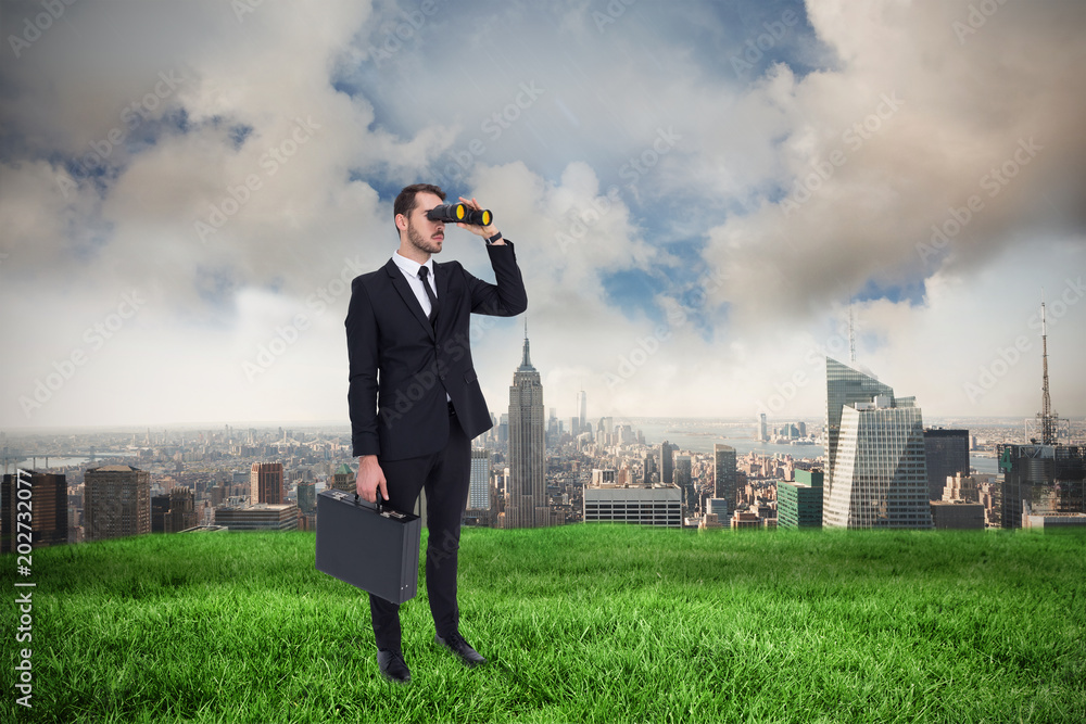 Canvas Prints Businessman holding a briefcase while using binoculars  against cloudy sky over city