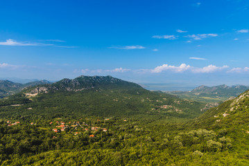 Naklejka na ściany i meble Montenegro landscape with balkan mountain village and rocks by cloudy day. Montenegrin wild nature scenery panoramic view with small town in the mountains valley. Freedom and adventure concept.