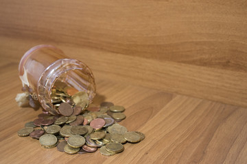 Jar of glass full of euro coins on a wood table