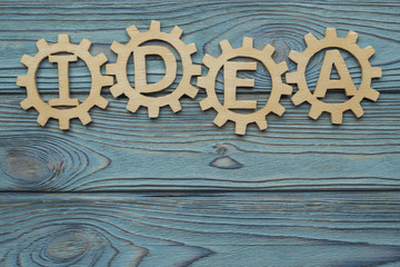 word IDEA from the gears of the parts of the puzzle. Business concept. Innovations, cooperation, teamwork. Strategy, creative. Copy space for text design. From natural wood, on a blue background