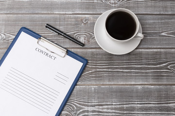 cup of coffee, ballpoint pen, blank contract blank on a wooden background. business.