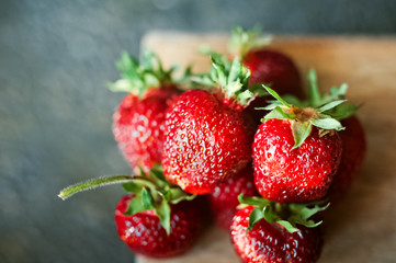 Ripe juicy beautiful red strawberry on a wooden dark background closeup