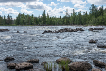 Landscape with river, rapids, rocks, forest and blue sky with clouds 