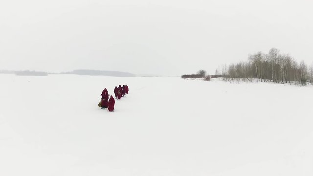 A group of people traveling on the taiga or snow-covered forest follow each other. Footage. Group of some people on winter hike in mountains, backpackers walking on snowy forest