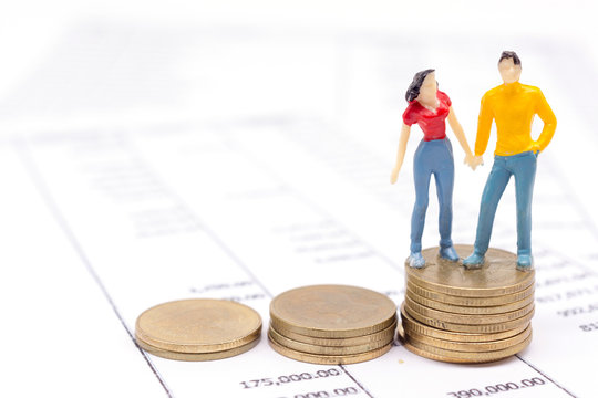 Miniature couple people and stack coins on statement. saving and loan concept.