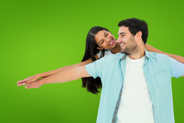 Obraz premium Happy casual man giving pretty girlfriend piggy back against green vignette