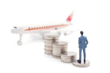 Miniature businessman standing on coins and the airplane behind. saving and loan concept.