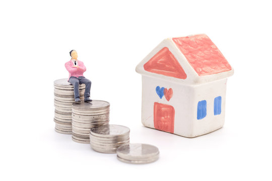 Miniature businessman standing on coins and the house behind. saving and loan concept.