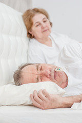 elderly woman with sick husband on the bed