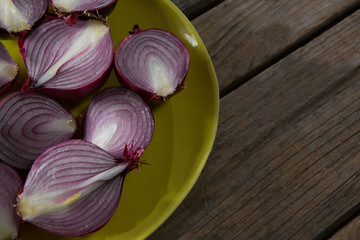 Halved onions in a plate on wooden table