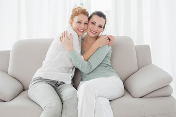 Obraz premium Cheerful young female friends embracing in living room