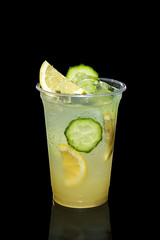 Cold Lemon and cucumber cocktail with a sparkling wine with ice cubes in take away glass isolated...