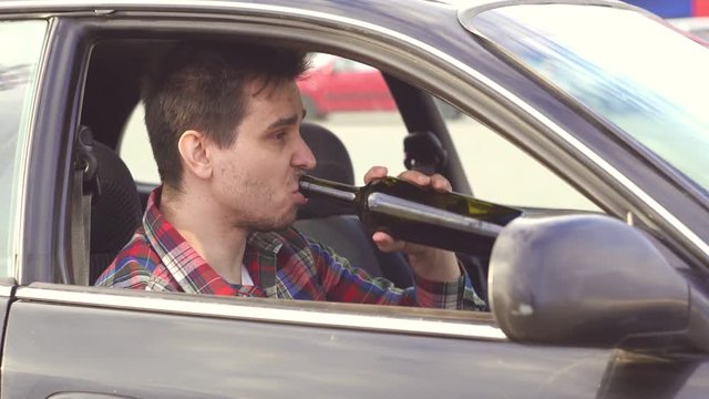 man in a shirt drinks in a car alcohol