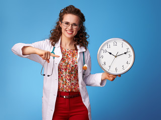 happy paediatrician doctor pointing at clock on blue
