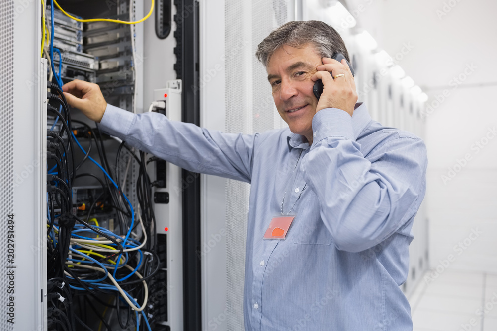 Poster man fixing server wires and talking on phone