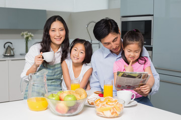 Family of four enjoying healthy breakfast in kitchen