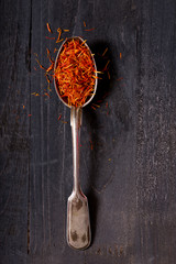 dried saffron spice in a spoon on wooden table