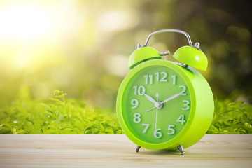 green alarm clocks on wood table nature background