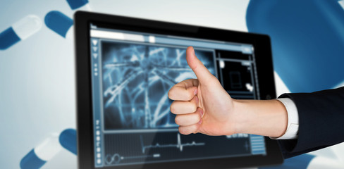 Hand showing thumbs up against cells on a digital tablet