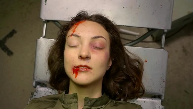 Portrait of an unconscious woman lying on table in dark asylum alone.
