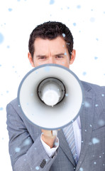 Composite image of Angry businessman shouting through a megaphone with snow falling