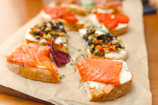 small sandwiches tapas with soft cheese and salmon on wood table