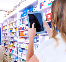 Woman using tablet pc against close up of shelves of drugs