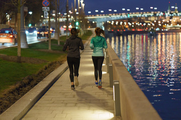 Sport activity on the Moscow embankment. Two women-runners in the night.