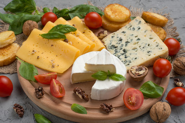 Different kinds of cheeses, with basil, cherry tomatoes, croutons from baguettes.
