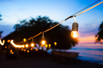 Beach promenade at sunset with party lights - obrazy, fototapety, plakaty