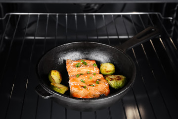 Frying pan with tasty fish fillets in oven