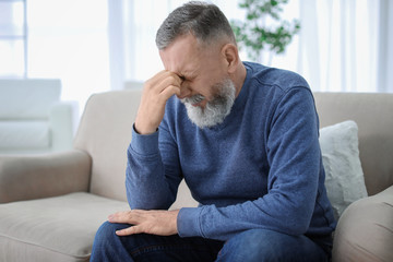 Mature man suffering from headache at home