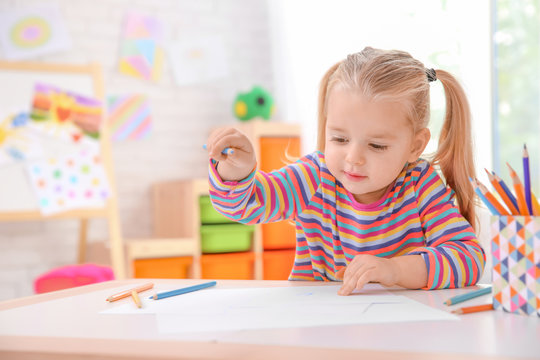 Little cute girl drawing at table indoors