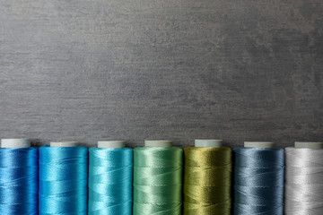 Color sewing threads on gray background, top view