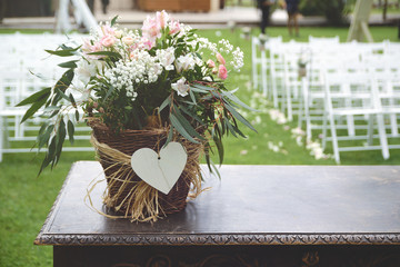 Bunch of flowers on a wooden desk against the white chairs aisle in a wedding celebration. Empty copy space for Editor's content.