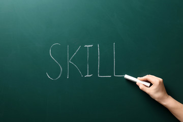 Woman writing word SKILL on chalkboard. Business trainer concept