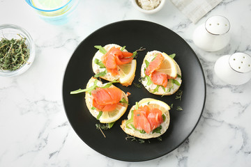 Plate of tasty sandwiches with fresh sliced salmon fillet on table, top view