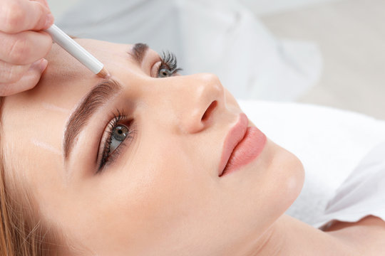 Cosmetologist preparing young woman for  eyebrow permanent makeup procedure, closeup