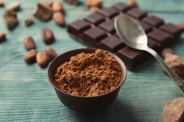 Composition with cocoa powder and chocolate bar on wooden background