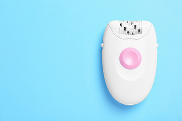 Modern epilator on color background