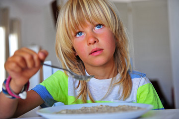 Little boy having breakfast in kitchen
