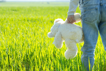 Little cute girl in the grass holding bear