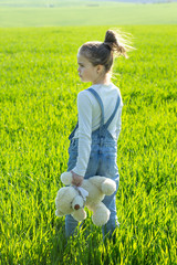Little cute girl in the grass holding bear