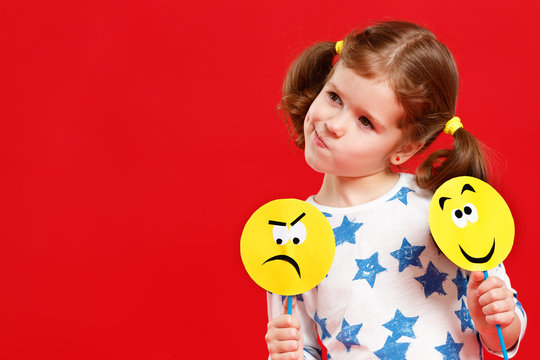 concept of children's emotions. child girl chooses between a sad and joyful smile