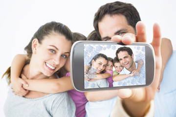 Hand holding smartphone showing smiling young family looking at camera together