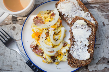 Scrambled eggs with bacon, sausage and onion with wholegrain bread and coffee