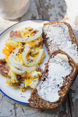 Scrambled eggs with bacon, sausage and onion with wholegrain bread and coffee