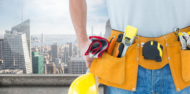Technician with tool belt around waist against large city