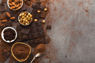 Crushed chocolate bar pieces and cocoa on gray background, top view