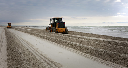 Two Graders adjusting send level on the beach. Beach Maintenance.
